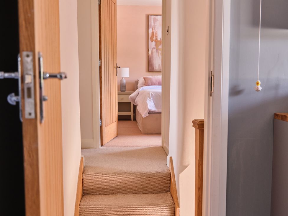 A hallway leading to a bedroom with a bed and nightstand at 27 West Green in Heighington