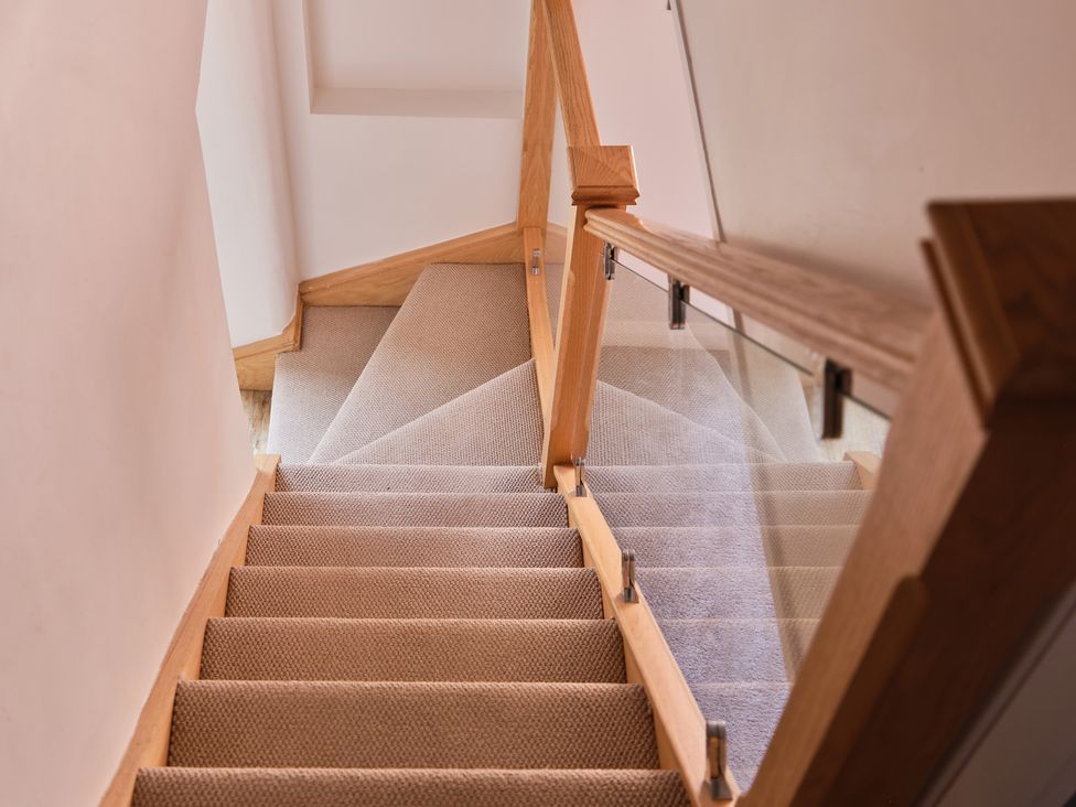 A staircase with carpet and wooden handrail at 27 West Green in Heighington