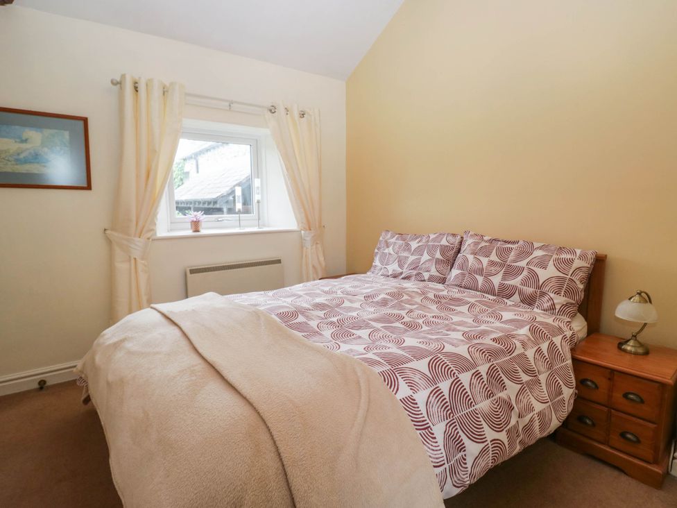 A bedroom with a bed and window at The Spinney near Milnthorpe