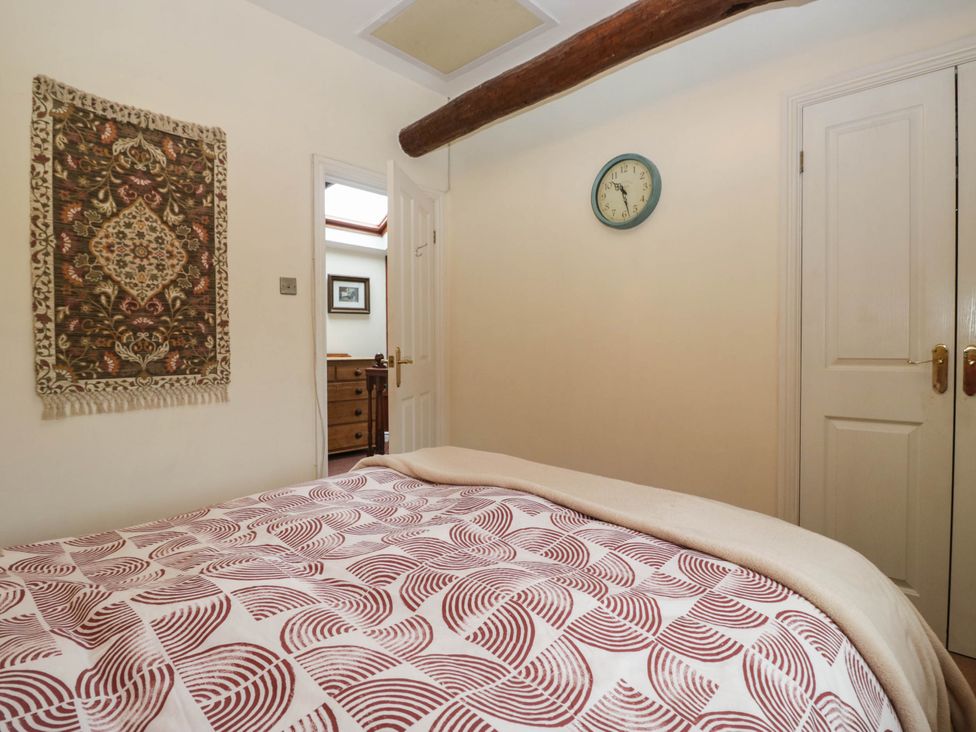 A bedroom with a bed and wall clock at The Spinney near Milnthorpe