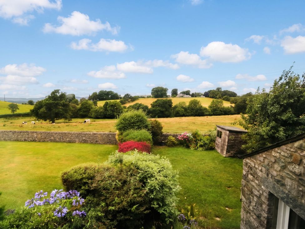 A garden with flowers and a shed overlooking fields at The Spinney near Milnthorpe