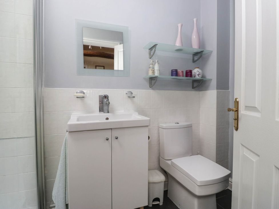 A bathroom with a sink, toilet, and shelf at The Spinney near Milnthorpe
