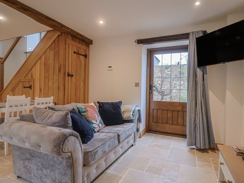 A living room with a sofa and door at Rose Cottage in Wellington