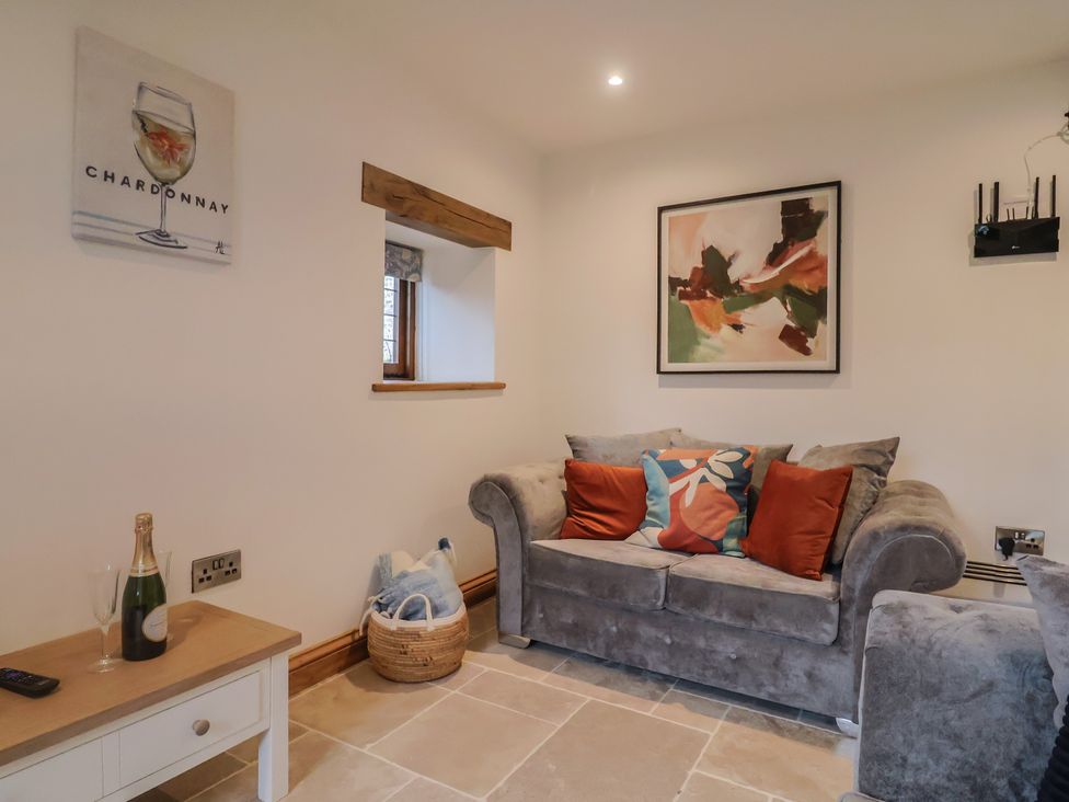 A living room with a grey sofa and champagne at Rose Cottage in Wellington