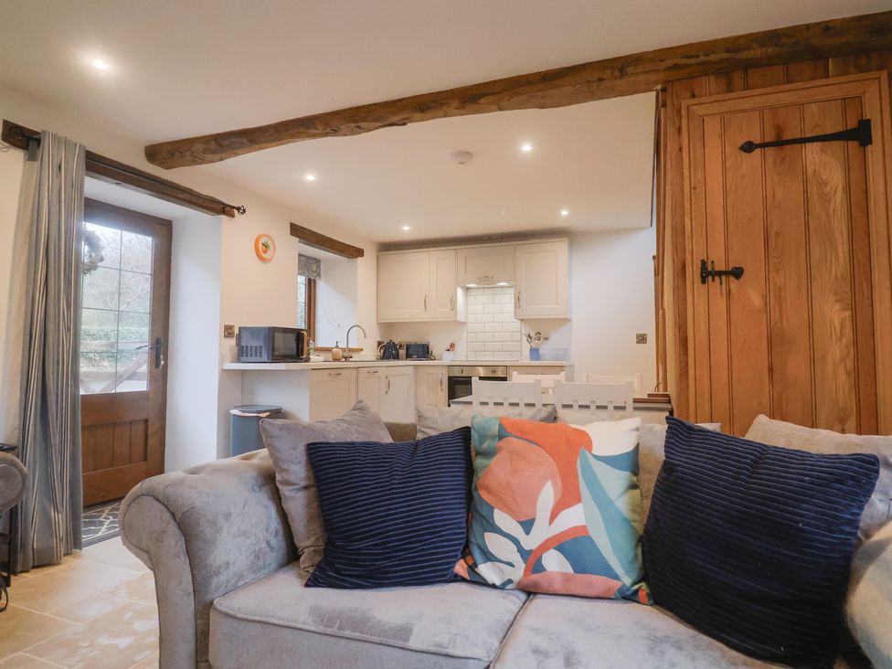 A living room with a couch and kitchen area at Rose Cottage in Wellington