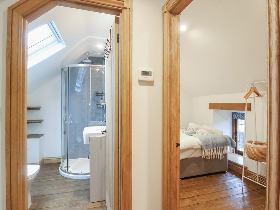 A bathroom with a shower and toilet next to a bedroom at Rose Cottage in Wellington
