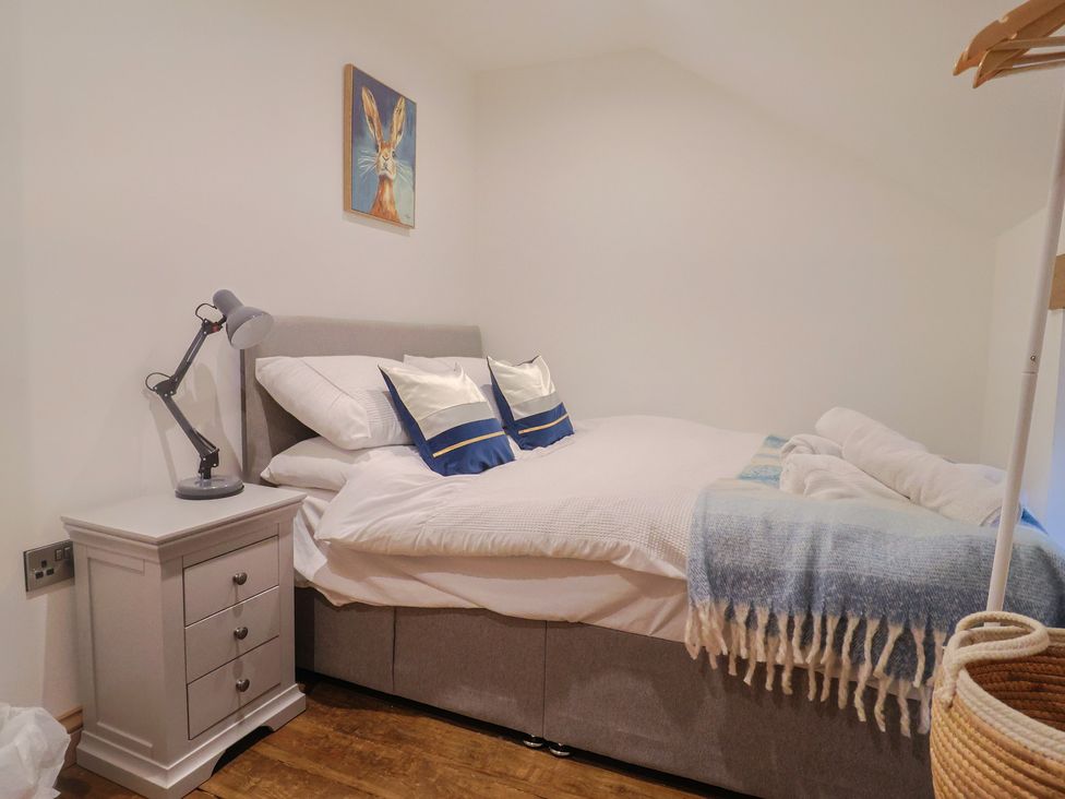 A bedroom with a bed and a bedside table at Rose Cottage in Wellington