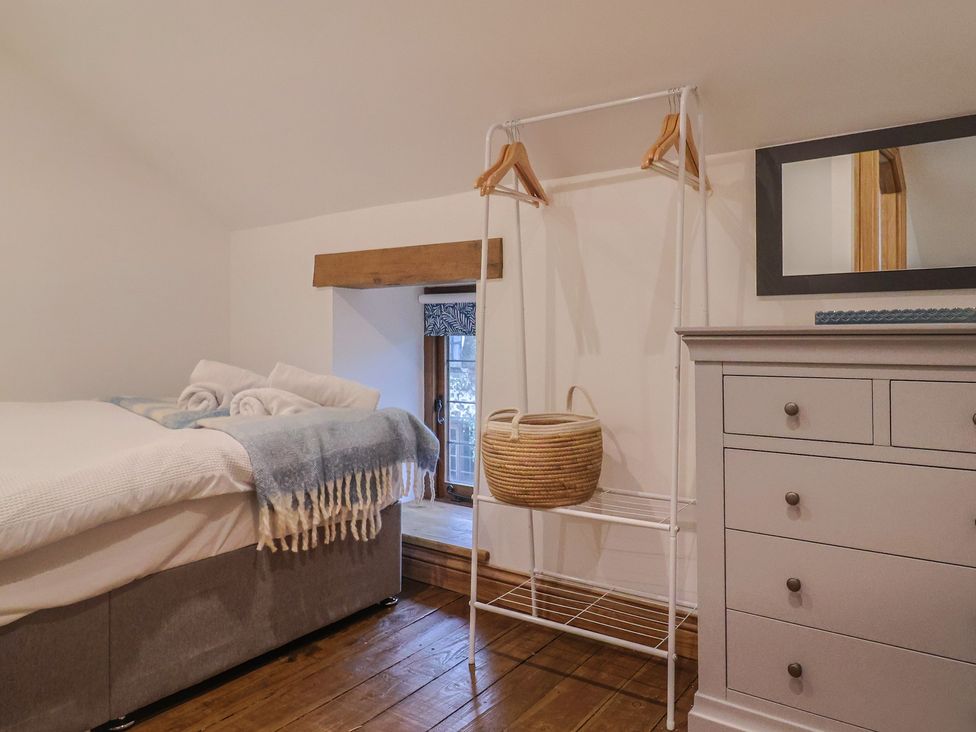 A bedroom with a bed and hanging rail at Rose Cottage Wellington
