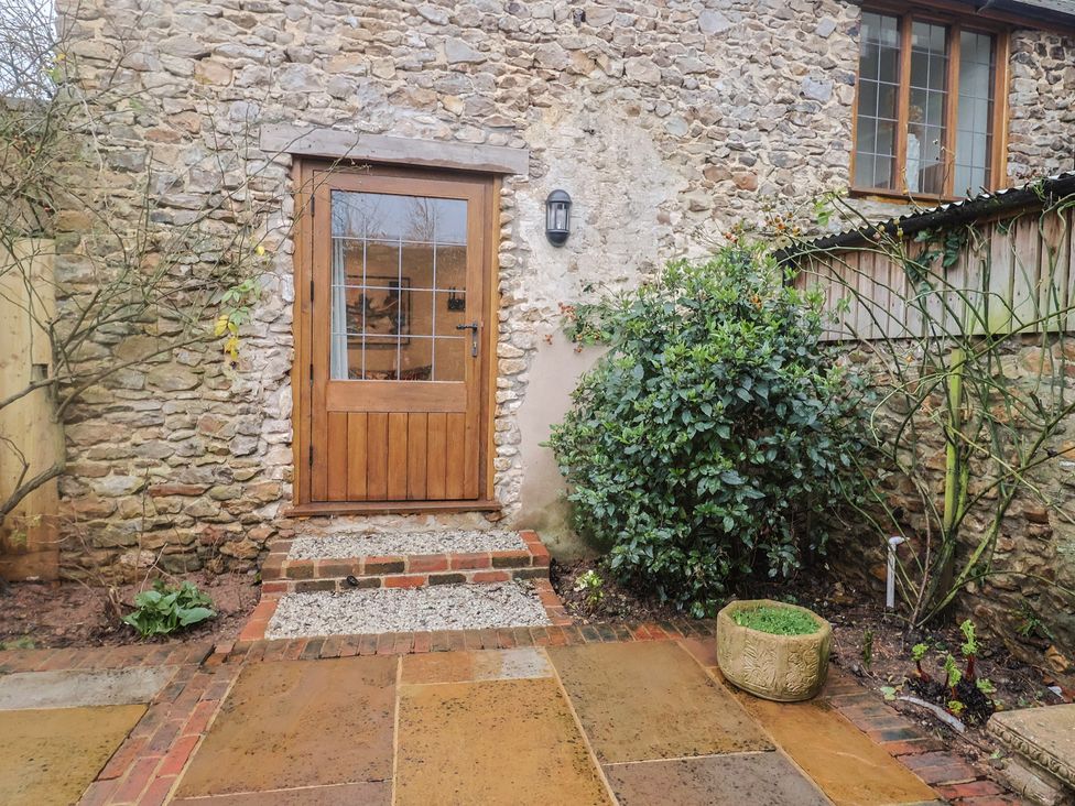 An entrance with a wooden door and stone wall at Rose Cottage in Wellington