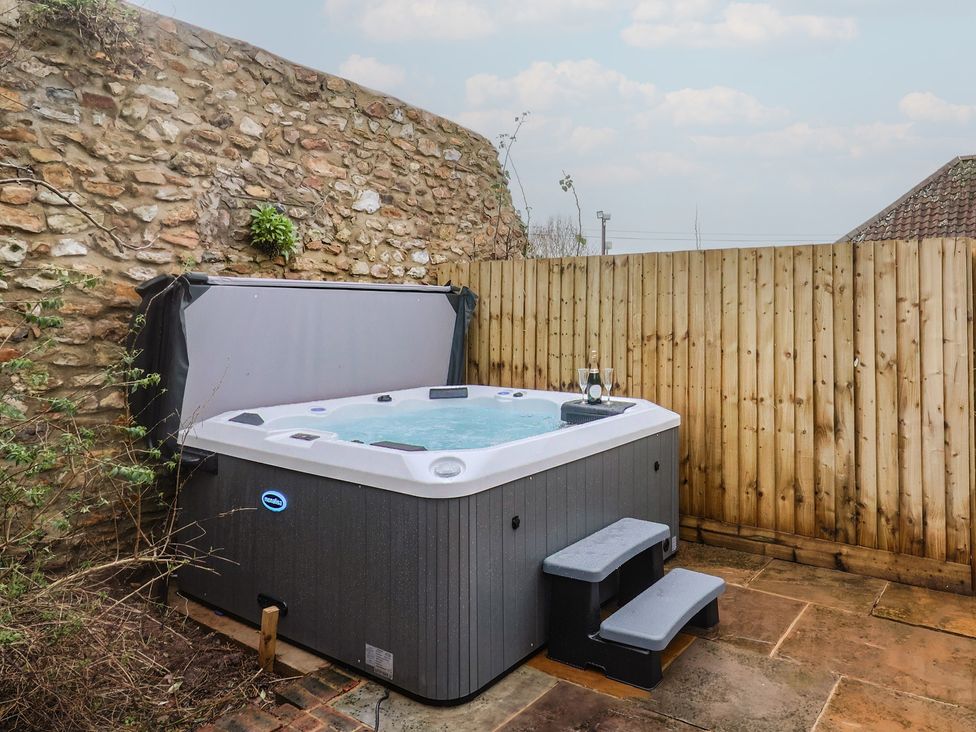 A hot tub with steps beside a wall and fence at Rose Cottage in Wellington