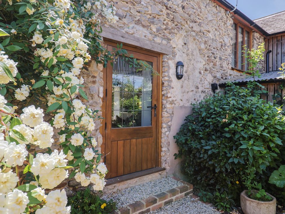 An entrance with a wooden door surrounded by flowers at Rose Cottage in Wellington