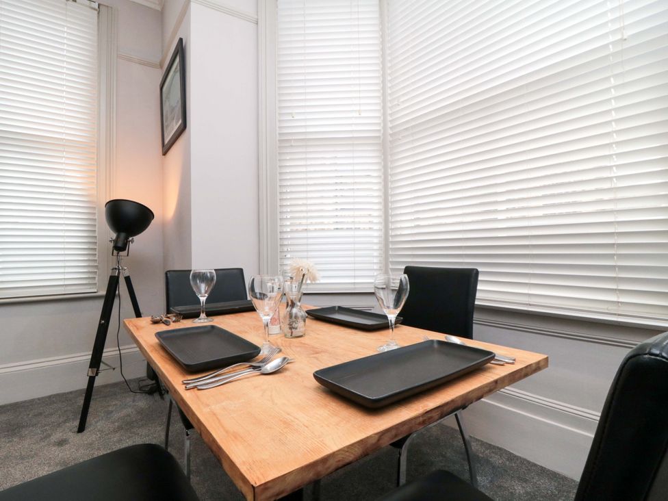 A dining area with a wooden table and black chairs at Ground Floor 1 bed in Scarborough
