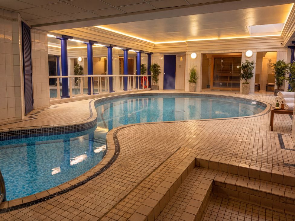 An indoor pool area with tiled flooring and plants at Craven Suite in Scarborough