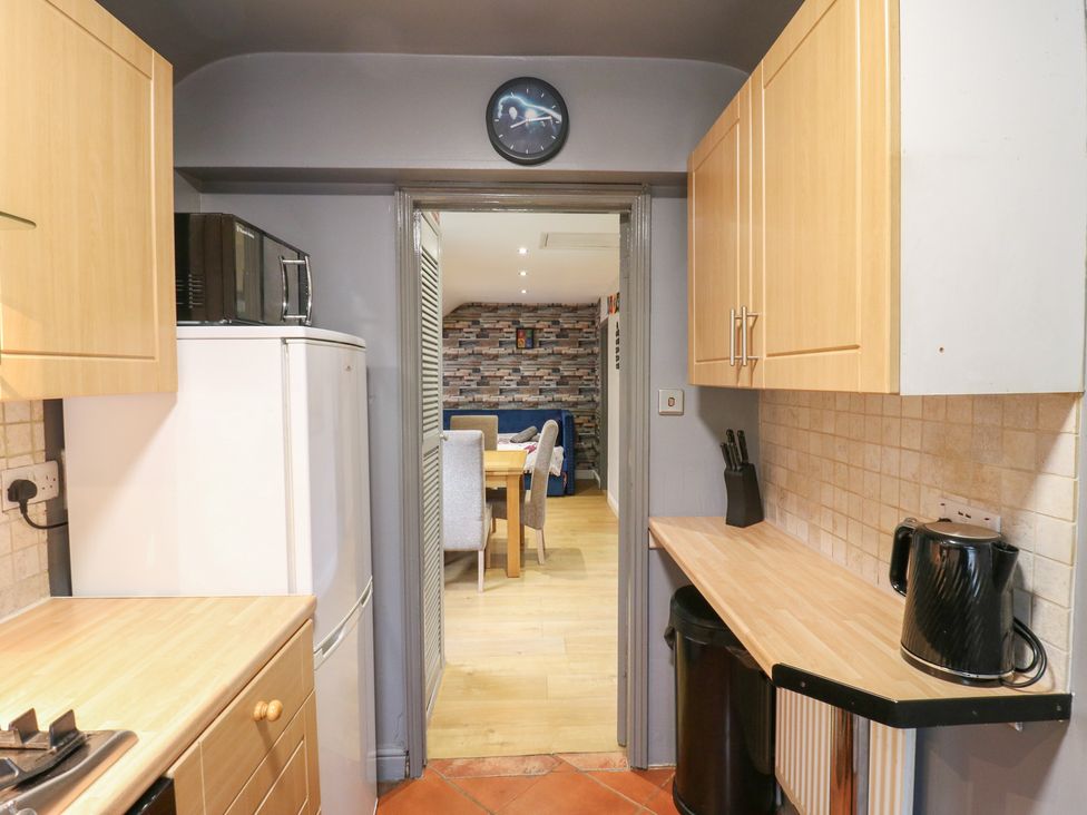 A kitchen with appliances and a view into a dining area at The Enchanted House in Watford
