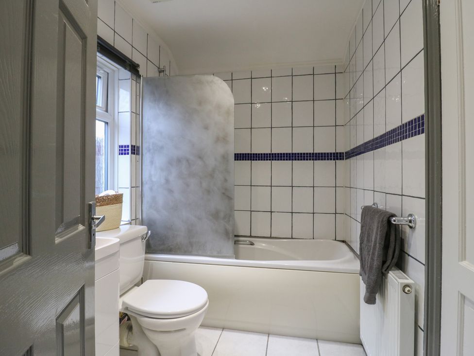 A bathroom featuring a bath tub, toilet, shower screen and window at The Enchanted House in Watford