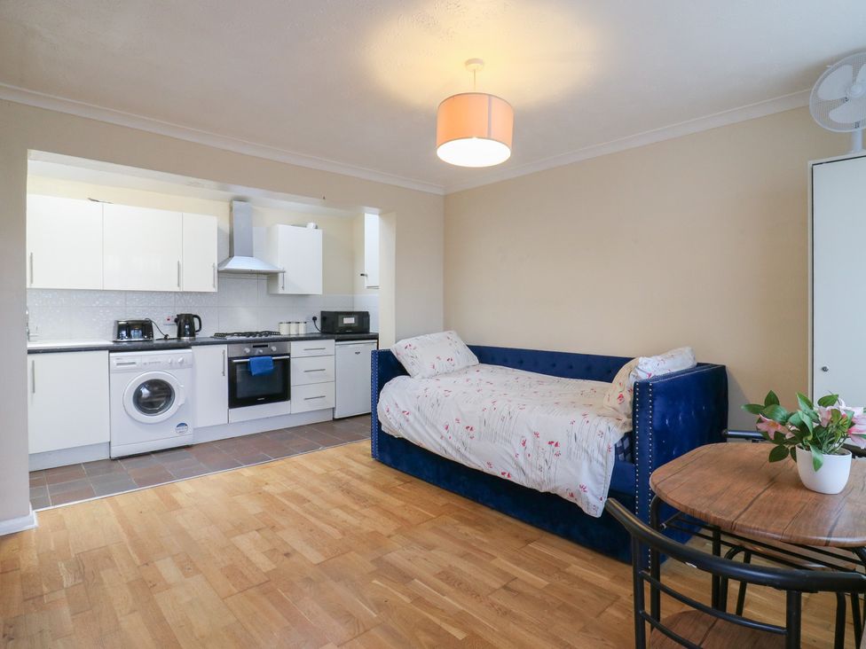An open plan living room with kitchen and sofa bed at Headmasters Hollow Watford