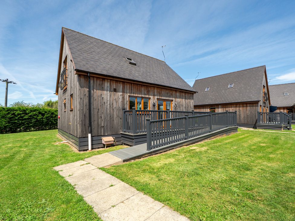A wooden house with a deck and grass area at James Ville Marina Lodge 7 Brigg