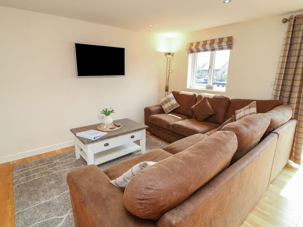 A living room with a sofa, coffee table, and television at James Ville Marina Lodge 8 in Brigg