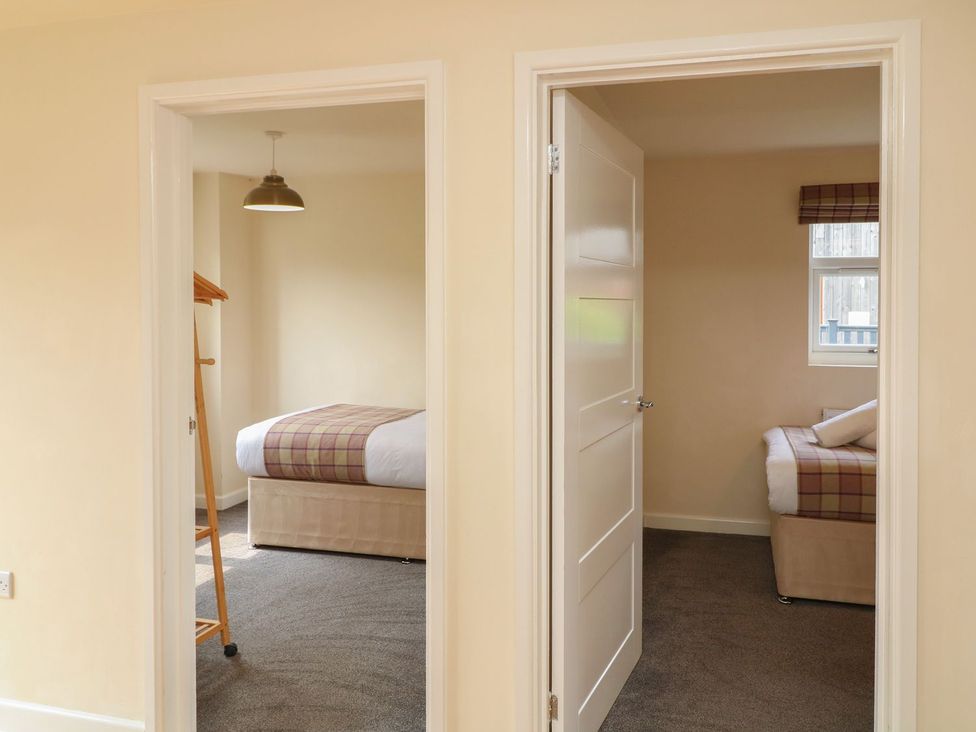 Two bedrooms with beds and light fixture at James Ville Marina Lodge 8 Brigg