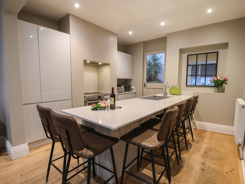 A kitchen with modern cabinets and bar stools at South Villa Sandsend near Whitby
