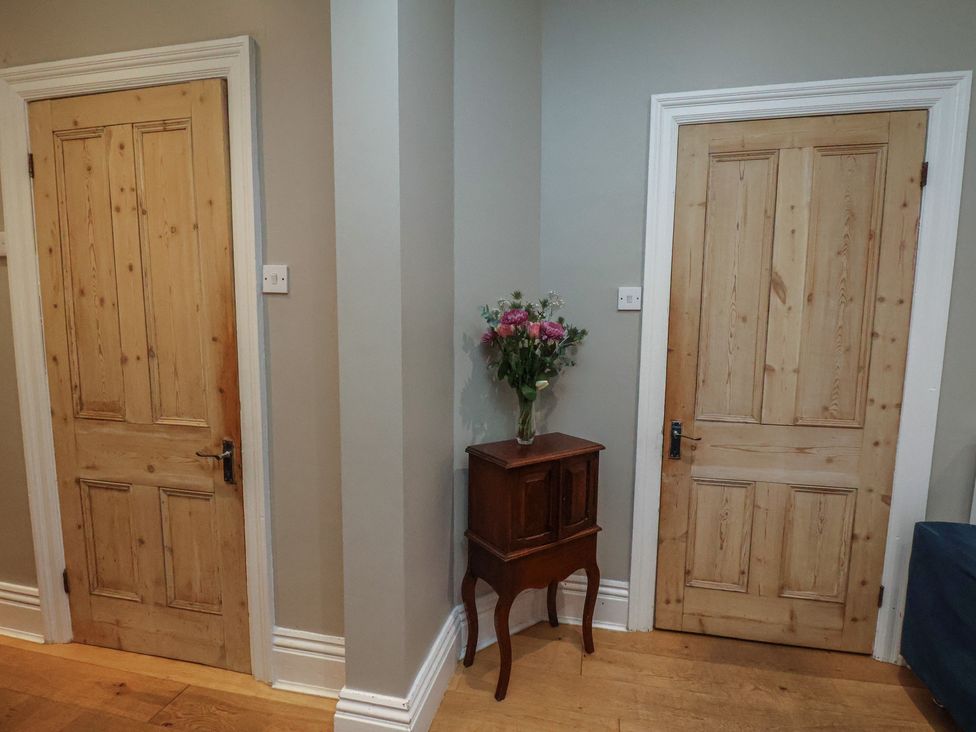 A hallway with wooden doors and a table with a vase and flowers at South Villa Sandsend near Whitby