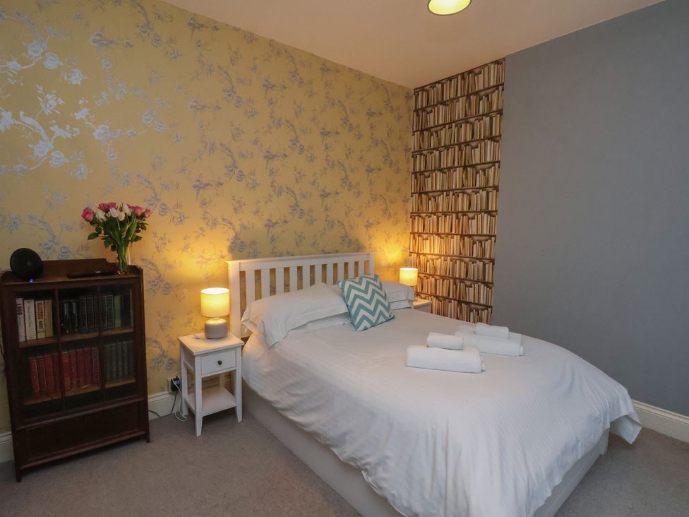 A bedroom with a bed, nightstand, and bookcase at South Villa in Sandsend near Whitby