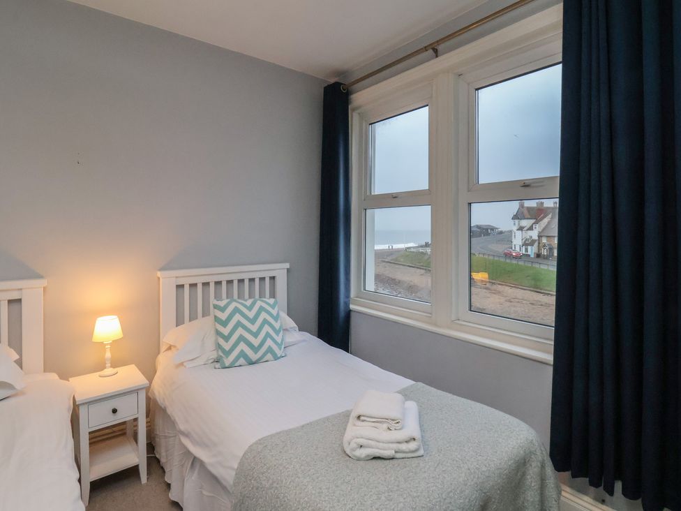 A bedroom with two beds beside a window at South Villa Sandsend near Whitby