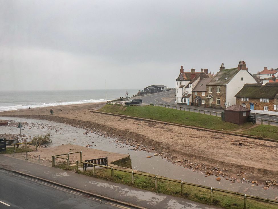 A beach with a view of houses and a road at South Villa Sandsend near Whitby