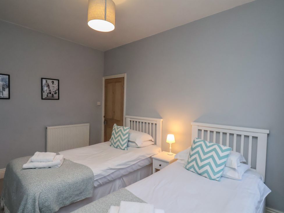A bedroom with two beds and a lamp at South Villa in Sandsend near Whitby