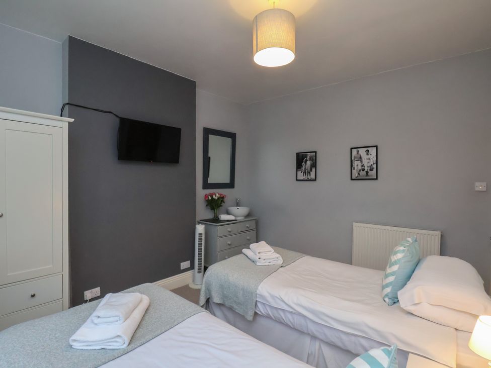 A bedroom with two beds and a television at South Villa Sandsend near Whitby