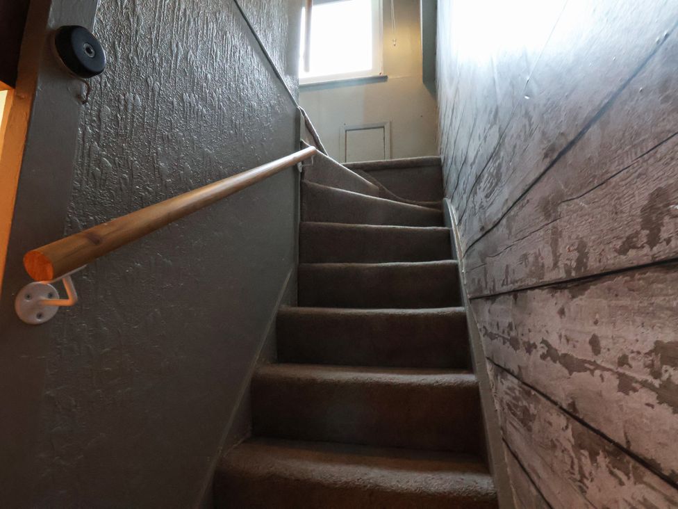 A stairwell with a window and wooden handrail at South Villa in Sandsend near Whitby