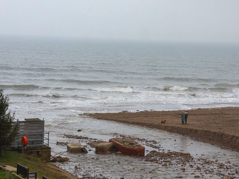 A beach with a sea and a boat at South Villa Sandsend near Whitby