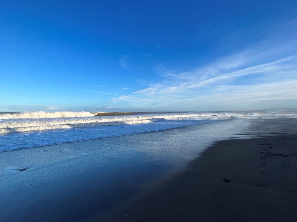 A beach with ocean waves and blue sky at South Villa Sandsend near Whitby
