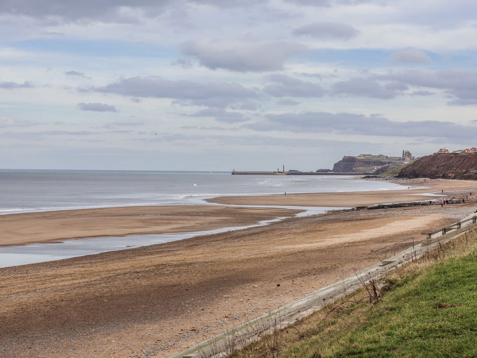 A beach with a view of the ocean and pier at South Villa in Sandsend near Whitby