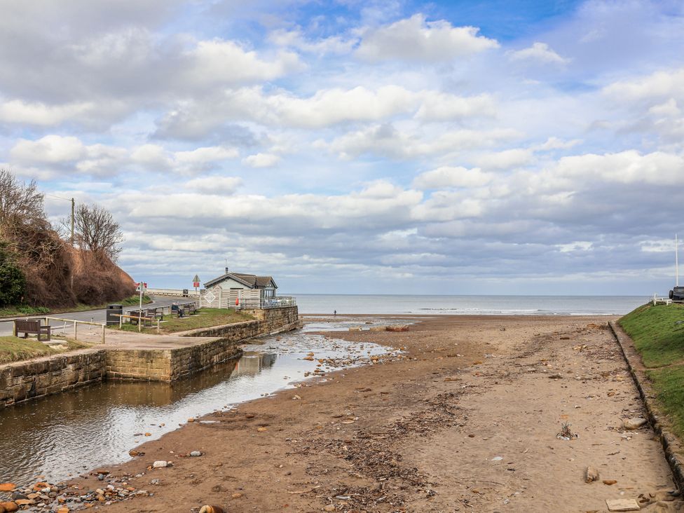 A beach with a building and river at South Villa in Sandsend near Whitby