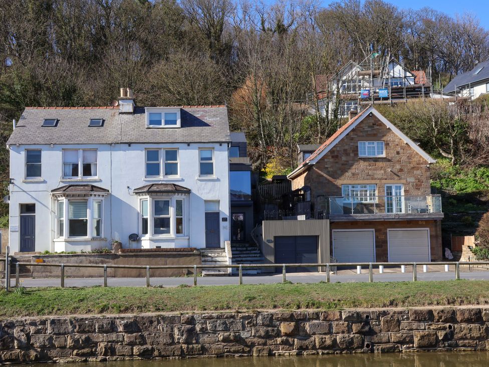 Two houses on a hillside with a road and fence at South Villa Sandsend near Whitby