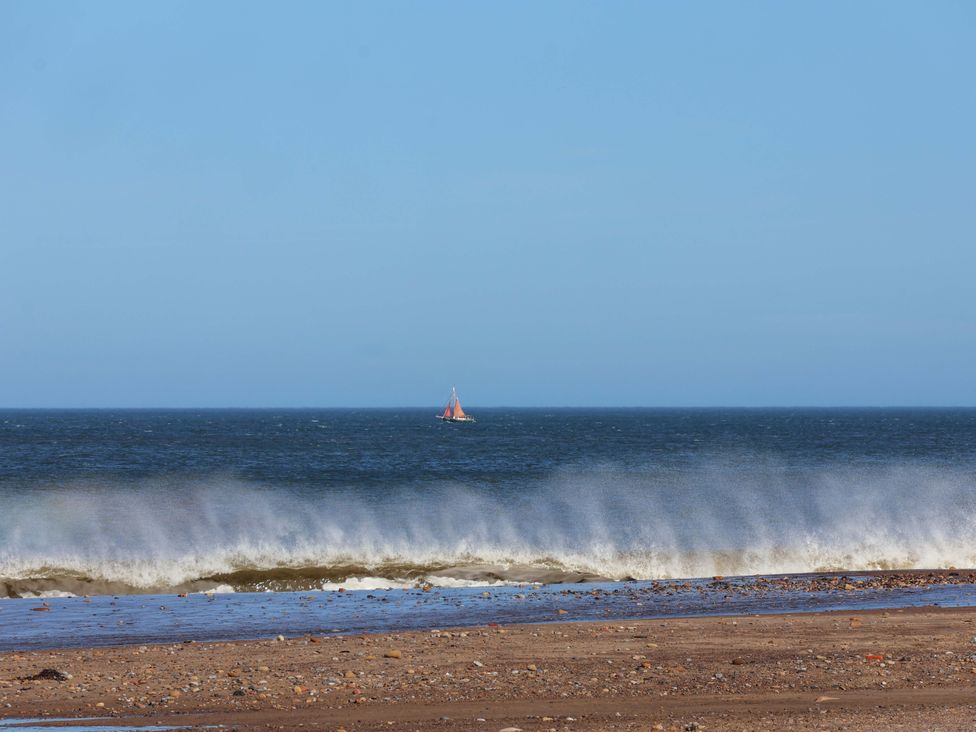 A beach view with waves and a boat at South Villa Sandsend near Whitby