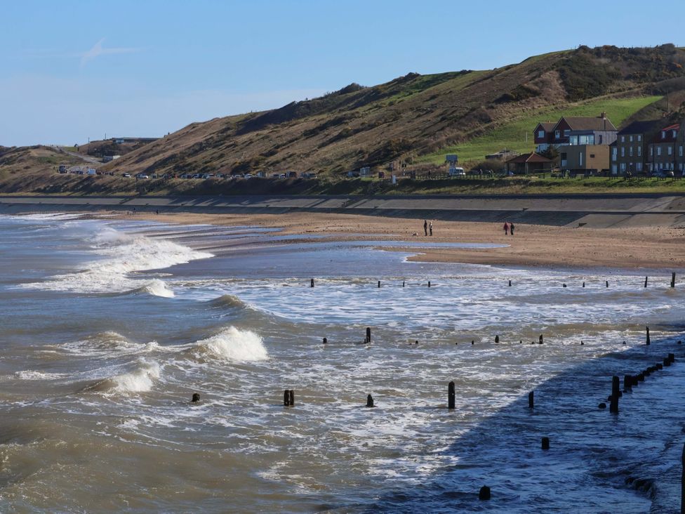 A beach with waves and houses along the shoreline at South Villa Sandsend near Whitby