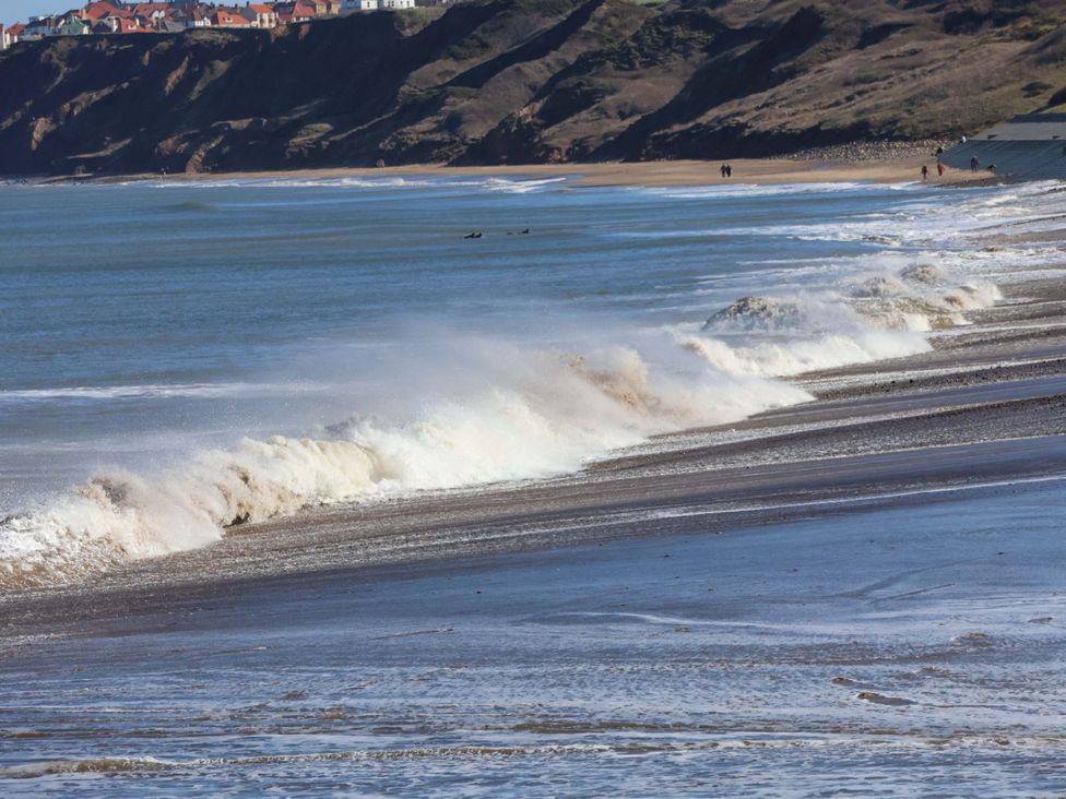 Ocean waves crashing on a beach with cliffs in the background at South Villa Sandsend near Whitby