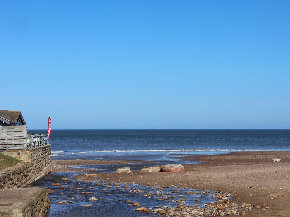 A beach with a building and flag at South Villa in Sandsend near Whitby