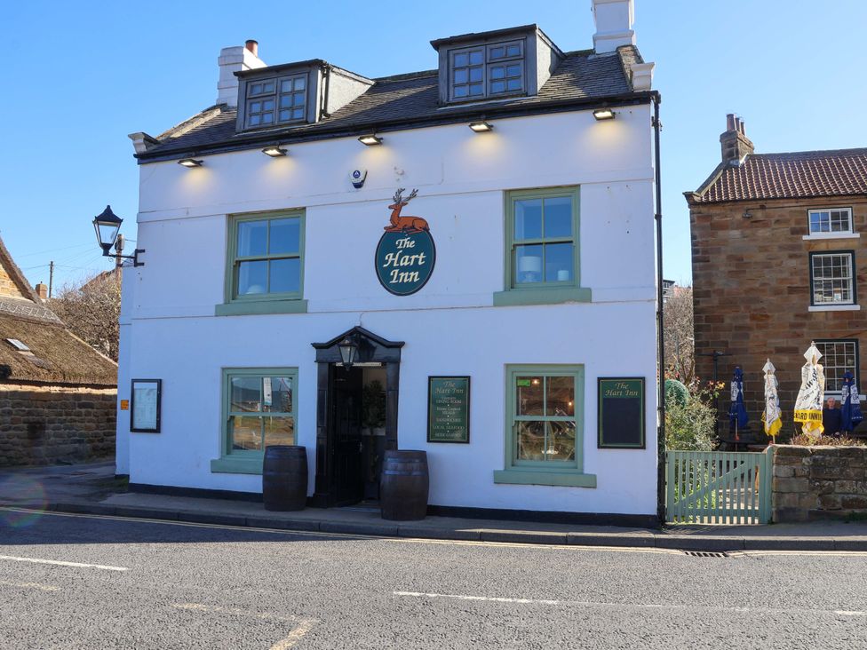 A pub exterior with signage and outdoor seating at The Hart Inn Sandsend near Whitby