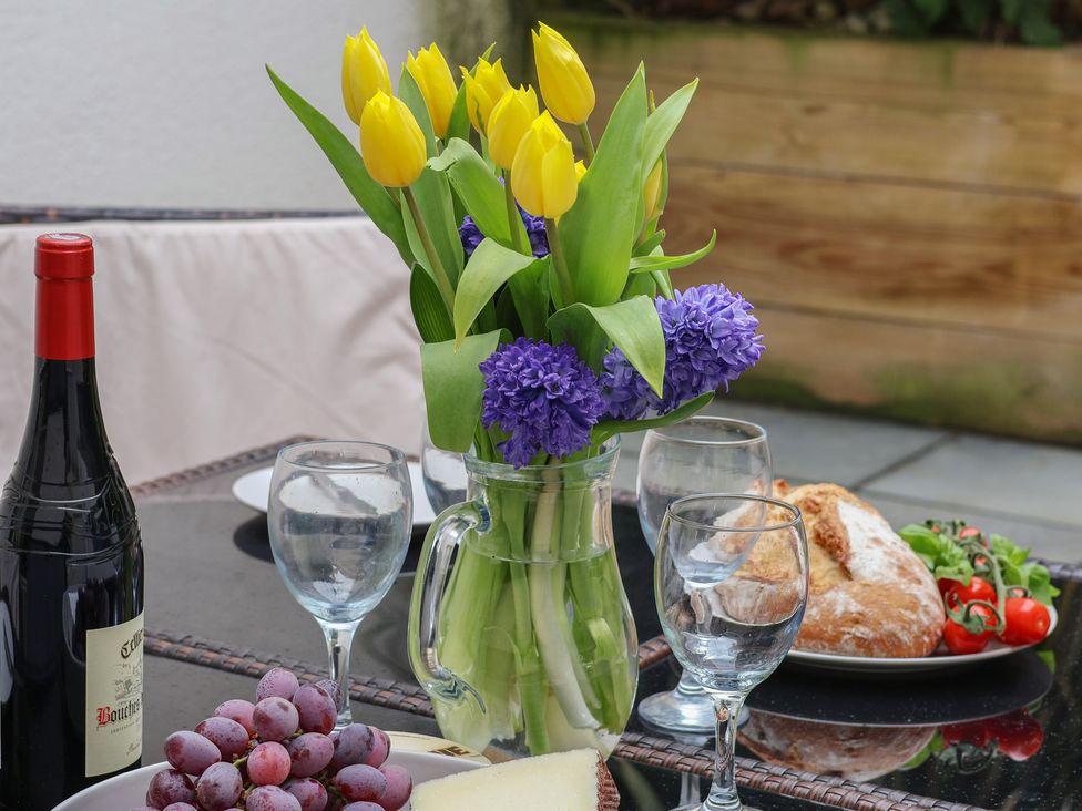 An outdoor dining area with a table set with flowers, wine, and food at South Villa Sandsend near Whitby