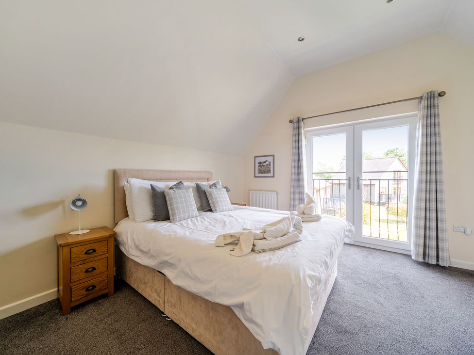 A bedroom with a large bed and a patio door opening to a balcony at James Ville Marina Lodge 9, Brigg