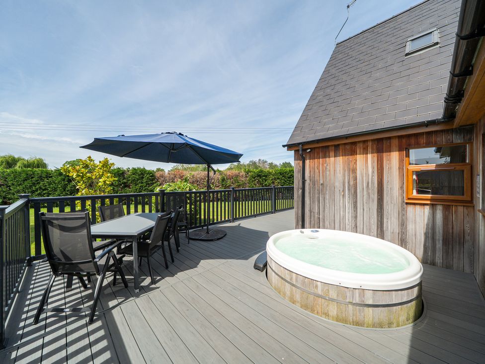 An outdoor deck with a hot tub and seating area at James Ville Marina Lodge 9 in Brigg