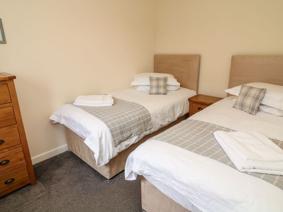 A bedroom with two beds and a bedside table at James Ville Marina Lodge 13, Brigg