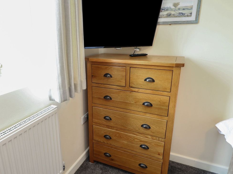 A bedroom with a dresser and television at James Ville Marina Lodge 13 in Brigg
