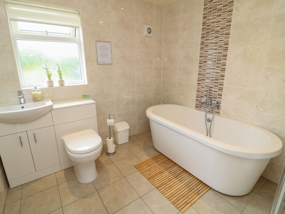 A bathroom with a bathtub, toilet, sink, and vanity unit at James Ville Marina Lodge 14 in Brigg