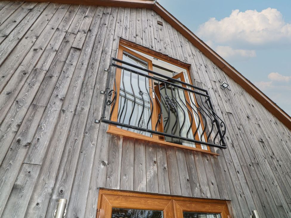 A window with a balcony railing on a wooden wall at James Ville Marina Lodge 14 in Brigg