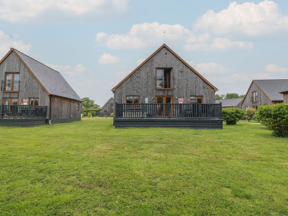 A row of wooden houses with decking and grass at James Ville Marina Lodge 14 in Brigg
