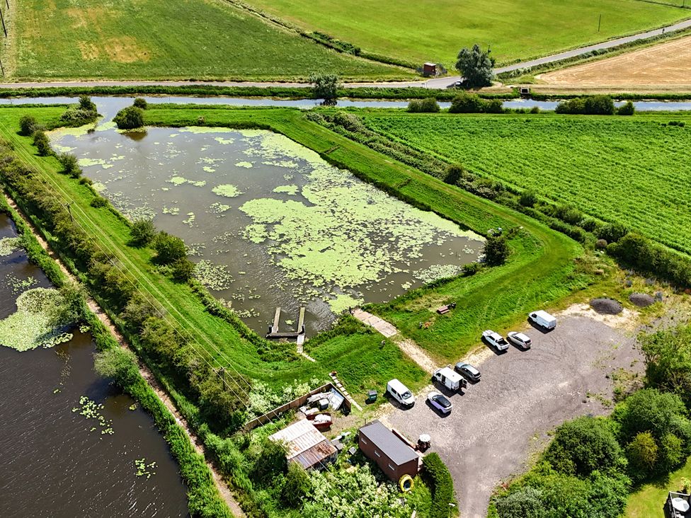 An aerial view of a pond surrounded by grass and vehicles at James Ville Marina Lodge 14 in Brigg